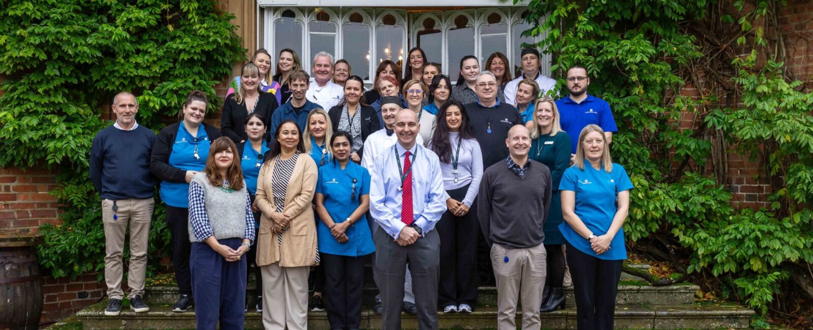 A group photo of Cumberland Lodge staff outside the Tapestry Hall doors