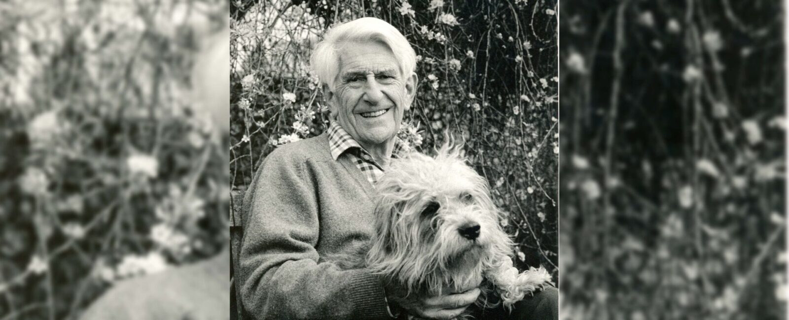 A black and white photo of Anthony Lloyd holding a dog