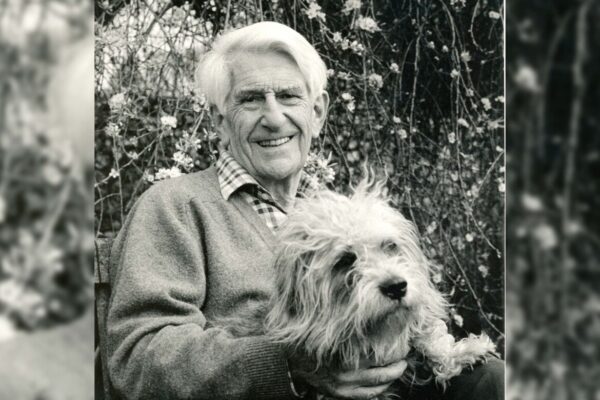 A black and white photo of Anthony Lloyd holding a dog